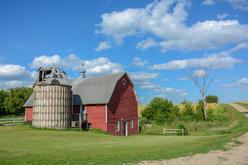 Obraz premium Red barn with gray shingled roof and old silo on a farm in rural Minnesota, USA. 