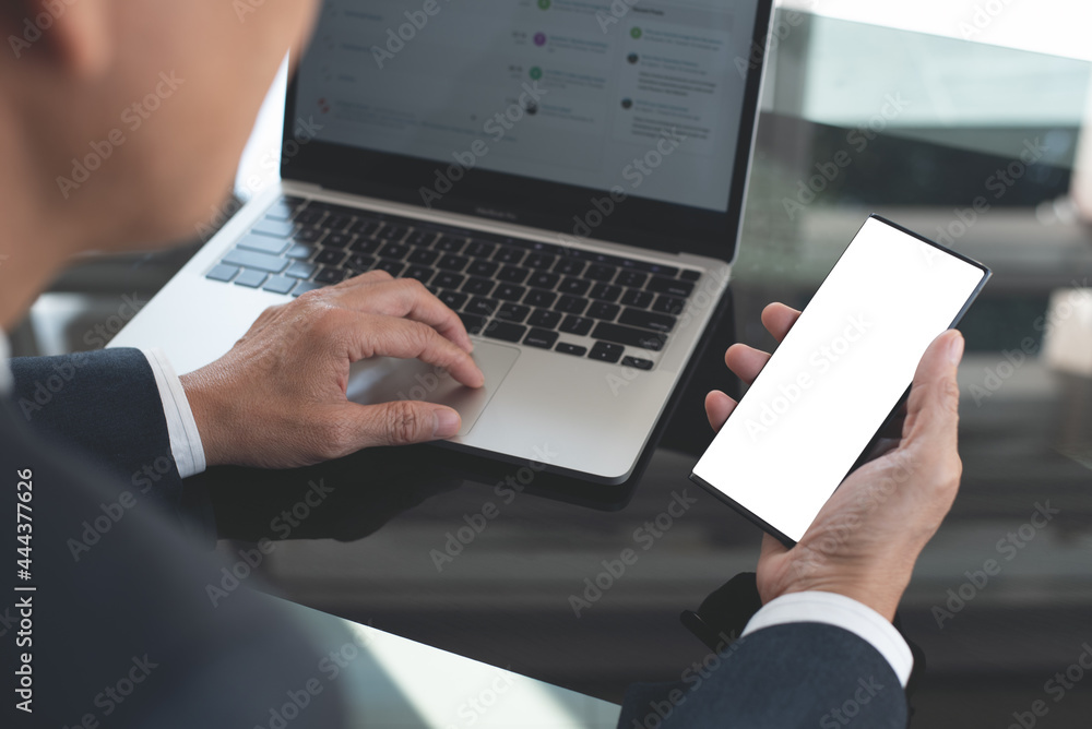 Sticker mockup image, business man hand holding black black mobile smart phone working on laptop computer on