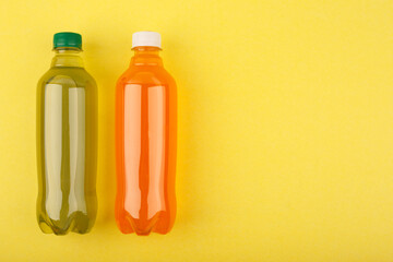 Colorful flat lay with orange and green refreshing soda drinks in transparent plastic bottles on...