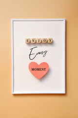 A white frame and an inscription in it: enjoy every moment. A call to joy in life