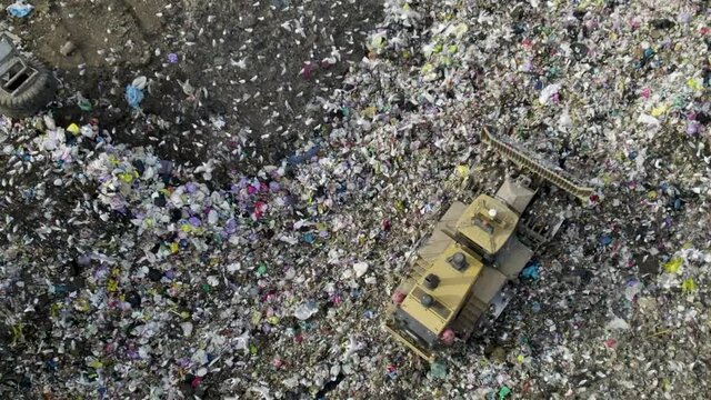 Bulldozer reversing over huge landfill site 