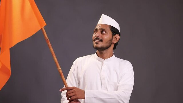 Young indian man (pilgrim) in traditional wear and waving religious flag.