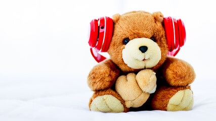 brown lovely fluffy teddy bear toy creatively wear red earphone placed on bed as lovely gift on delight celebration day