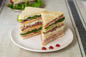 club sandwich with ham, tomatoes, lettuce and mayonnaise between slices of  bread 