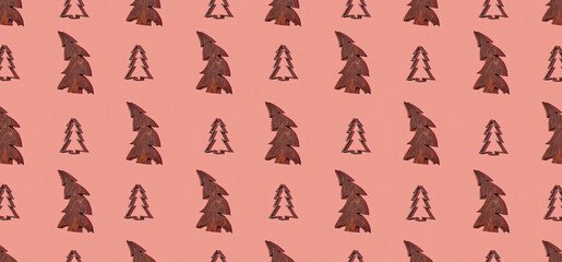 Pattern of wooden christmas trees on pink pastel background