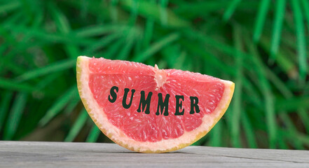 Slice grapefruit and message of summer. Palm leaves background.