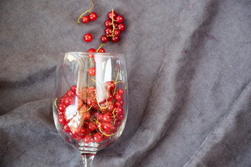Red currant in the wineglass on the gray cloth background. Large group.
