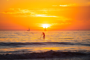 Fototapeta premium Paddle boarding. Sea beach with sunset sky abstract background. Copy space of summer vacation and travel concept.