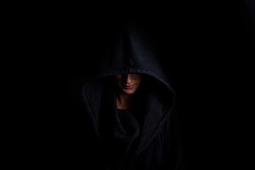 Young woman in a black hood on a dark black background - Powered by Adobe