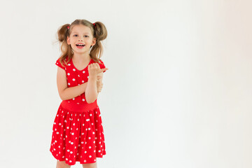 A little girl in a red dress points up at your ad on an isolated white background