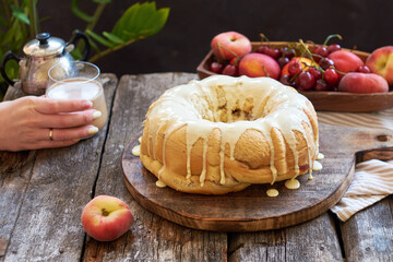 Buns with peaches and white chocolate. Fruits, coffee, wooden background, side view.