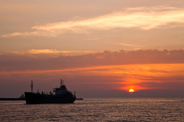 Fototapeta premium Sunset into the sea with the large ship silhouette in Kaohsiung, Taiwan.