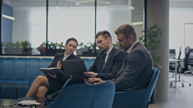 Team of colleagues sitting in office, discussing business tasks, cooperation