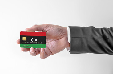 Bank credit plastic card with flag of Libya holding man in elegant suit