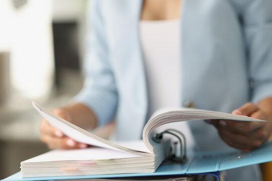 Woman examining information in folder with documents closeup