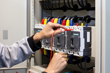 Electrical engineer tests the operation of the electric control cabinet on a regular basis for maintenance.	