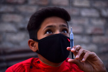13 years old Asian cute boy wearing protective mask, with syringe, prevention of Corona virus...