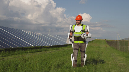 Man in exoskeleton walking in field near solar panels