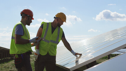Male engineers inspecting photovoltaic panel together