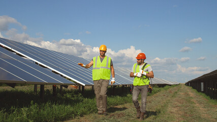 Male colleagues walking and talking on solar farm