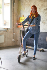 A young beautiful female employee standing on a scooter and posing for a photo in the office