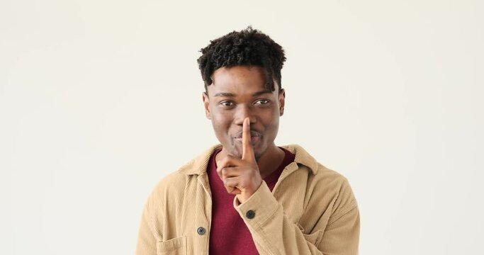 Man gesturing with finger on lips over white background