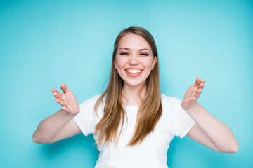 Obraz premium Happy girl smiles broadly and laughs and spreads her hands cheerfully, closing her eyes