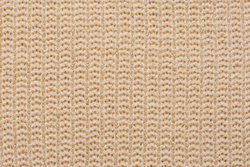 Macro view synthetic beige knitted fabric close up with golden knit. Knitting pattern of wool. Knitting Horizontal orientation beige wool texture background.