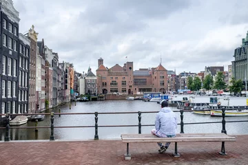 Fototapeten Een man zit op een bankje op het Damrak in Amsterdam © Holland-PhotostockNL