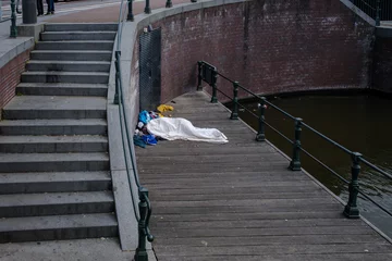 Fototapeten Slapende dakloze op een steiger onder het damrak in Amsterdam © Holland-PhotostockNL