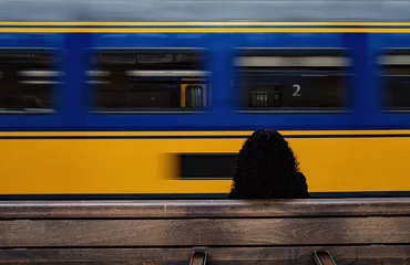 Fototapeten A lady is sitting on a bench on a platform in Amsterdam Central station    Een dame zit op een bankje op een perron in Amsterdam  Centraal station © Holland-PhotostockNL
