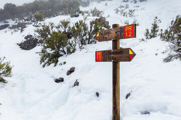 Directional sign plates surrounded by snow in Pico Ruivo footpath in Santana, Madeira island