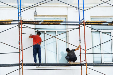 Facade restoration. Plasterers work while standing on the scaffolding. Preparing and plastering the wall for painting. Unrecognizable person. Space
