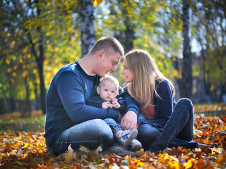 Happy family life concept. Caucasian parents (father, mother) and little son are walking, having fun and enjoying together on a sunny day. The family is resting in a green park. Family weekend.