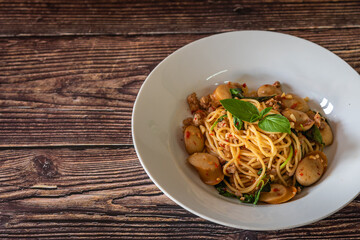 Stir fired spaghetti mix with minced pork, sausage, basil and chili as Thai and Italian mixing culture on this menu at wooden background