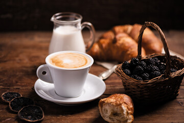Coffee cup with a croissant on a rustic wooden table