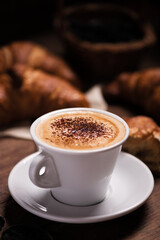 Coffee cup with a croissant on a rustic wooden table