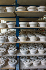 Fototapeta na wymiar Blanks of white ceramic unfired dishes standing in rows on metal racks at a porcelain factory in the Moscow region in Russia
