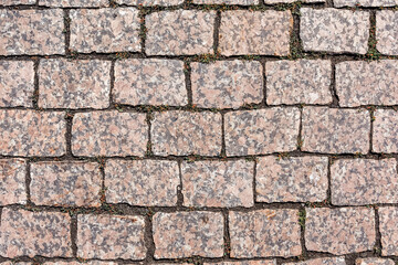 The sidewalk is paved with red granite paving stones. Natural background and texture of the stone. Top view.