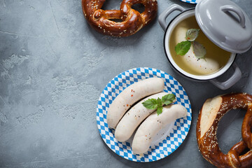 Weisswurst or german traditional white sausages with pretzels, flatlay over grey concrete background, horizontal shot with copyspace