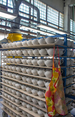 billets of ceramic white teapots in rows on the shelves in the production shop at the porcelain...