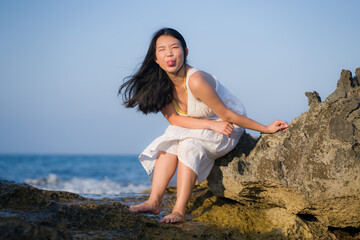 Fototapeta na wymiar young happy and beautiful Asian woman by the sea - Attractive Japanese girl in white dress enjoying relaxed summer holidays at tropical island in travel and lifestyle concept