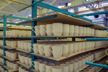 Blanks of white ceramic unfired dishes standing in rows on metal racks at a porcelain factory in the Moscow region in Russia