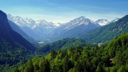 Obraz premium Panoramablick von Skiflugschanze in Oberstdorf auf Wald und Alpen mit Schnee unter blauem Himmel