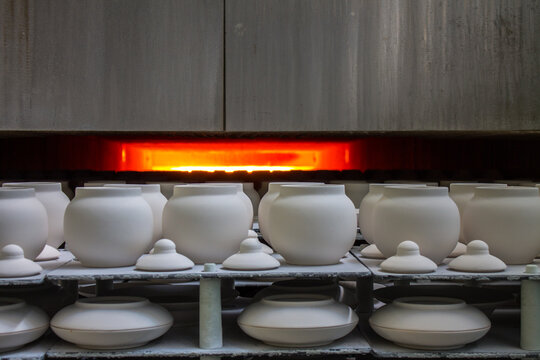 White blanks of unfired ceramic pots with lids on racks placed in a muffle kiln for firing close-up at a porcelain factory in the Moscow region