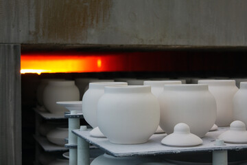 White blanks of unfired ceramic pots with lids on racks placed in a muffle kiln for firing close-up at a porcelain factory in the Moscow region