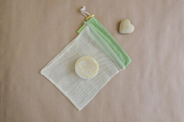 Round natural handmade soap on mesh packaging bag and souvenir stone heart on craft paper. Hygiene,...