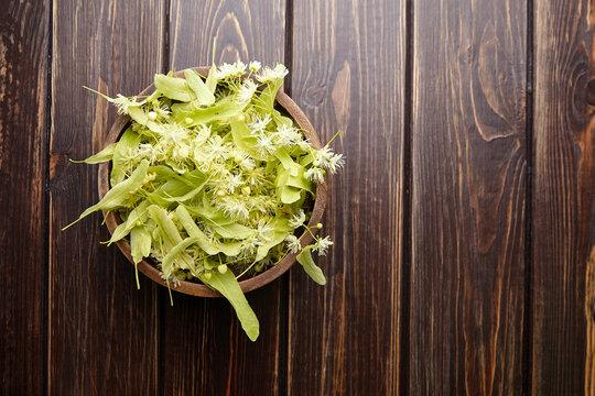 Linden flowers in wooden bowl on table