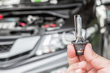 Close up car headlights xenon Lighting Equipment in hand a man with engine room for maintenance...