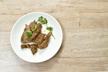 fried slice pork meat and liver with garlic couple pepper topping parsley on plate
